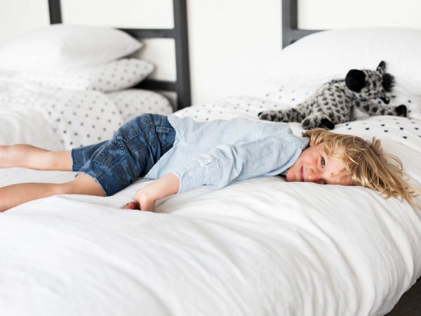 kid lying on white bed
