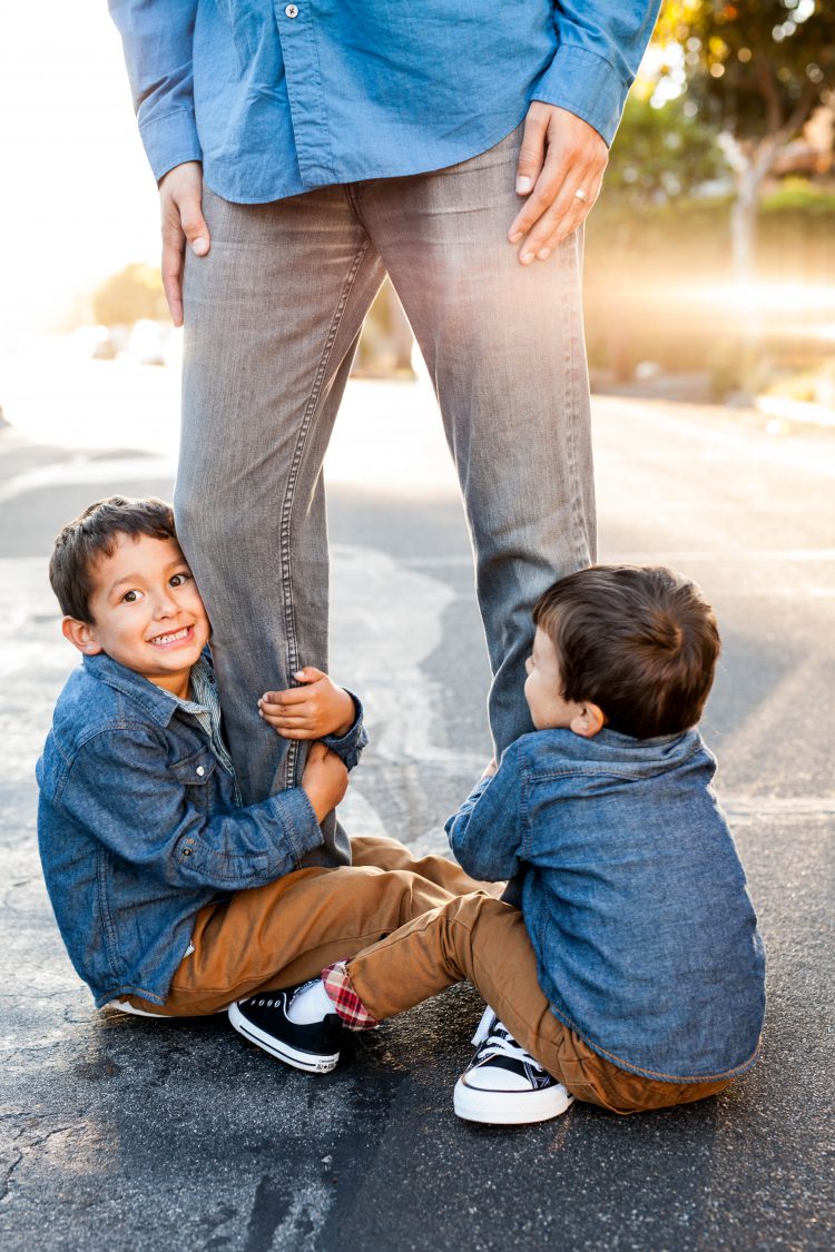 boys holding on to dad's legs