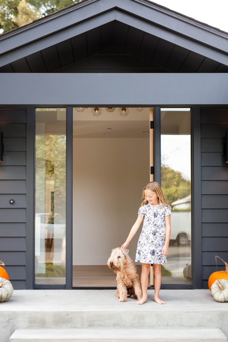 girl and dog outside a modern black house