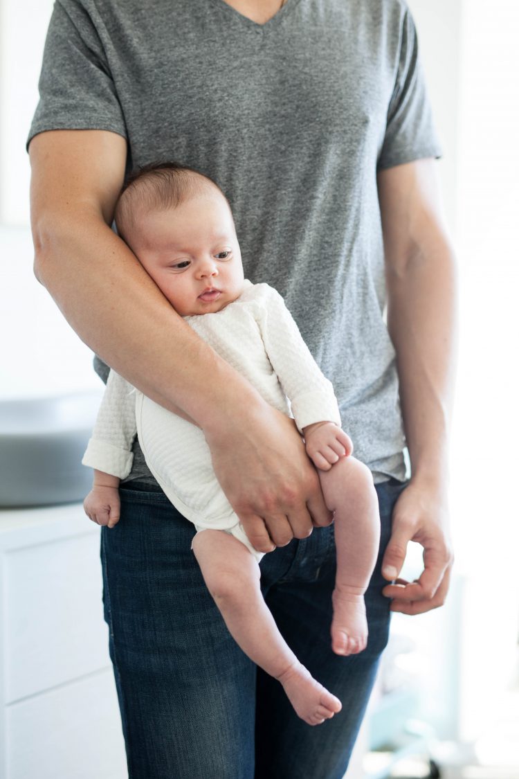 dad holding newborn baby on hip