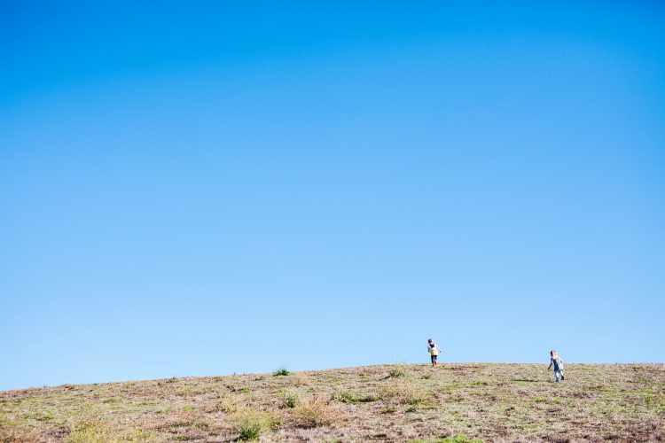 kids running up a hill with blue sky