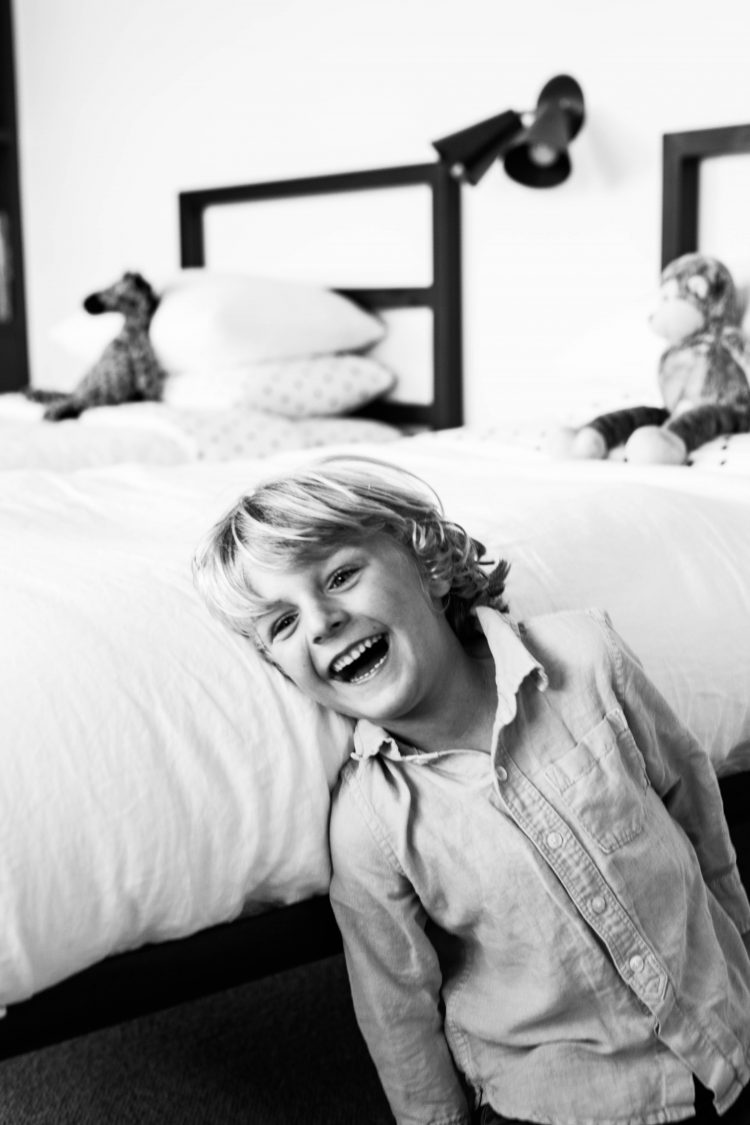 boy laughing on a bed in black and white